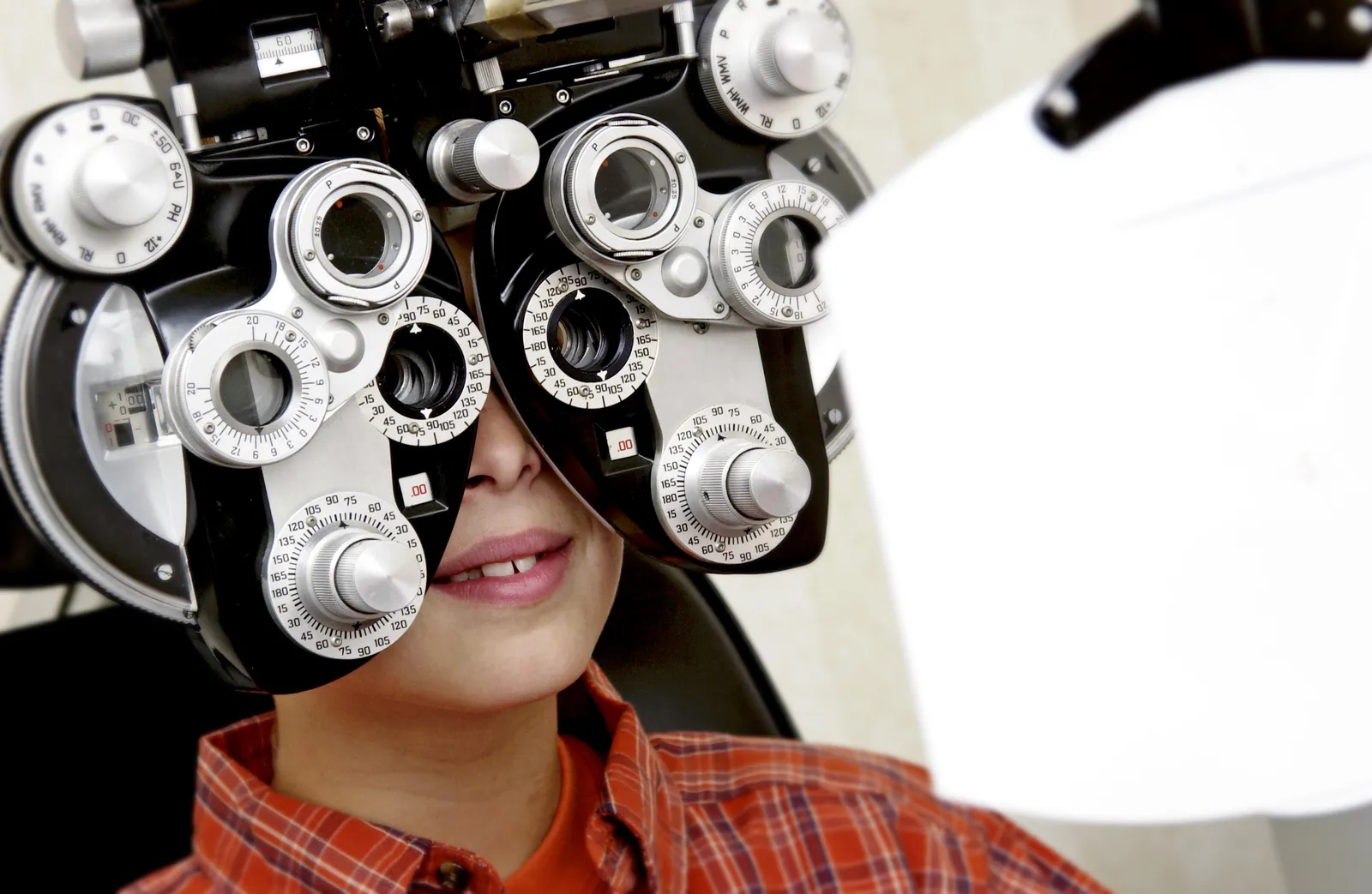 A child looking through a phoropter during a vision examination