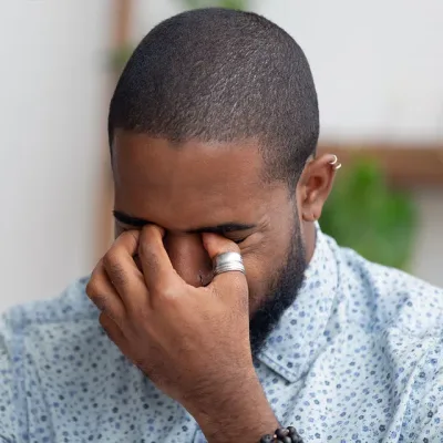 A man pinching the bridge of his nose with his eyes closed