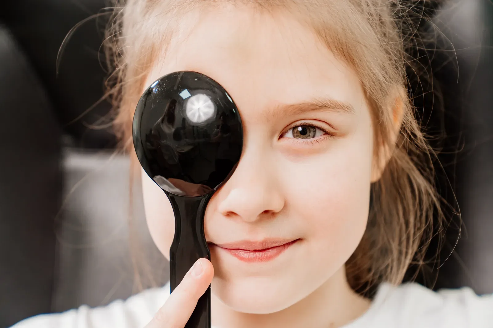 A child covering one eye with an occluder during a vision test