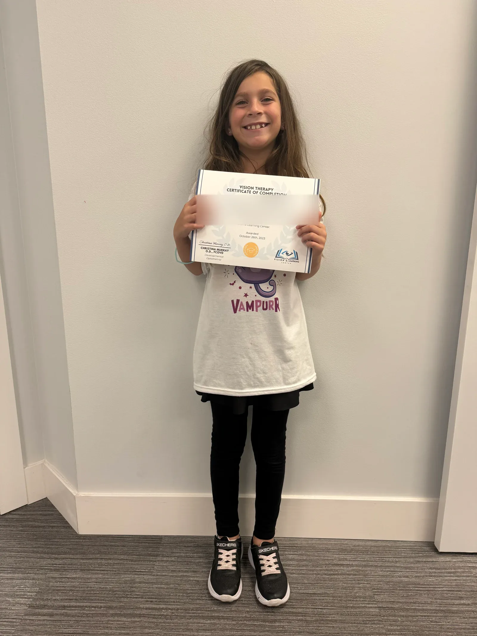 A vision therapy graduate holding their certificate