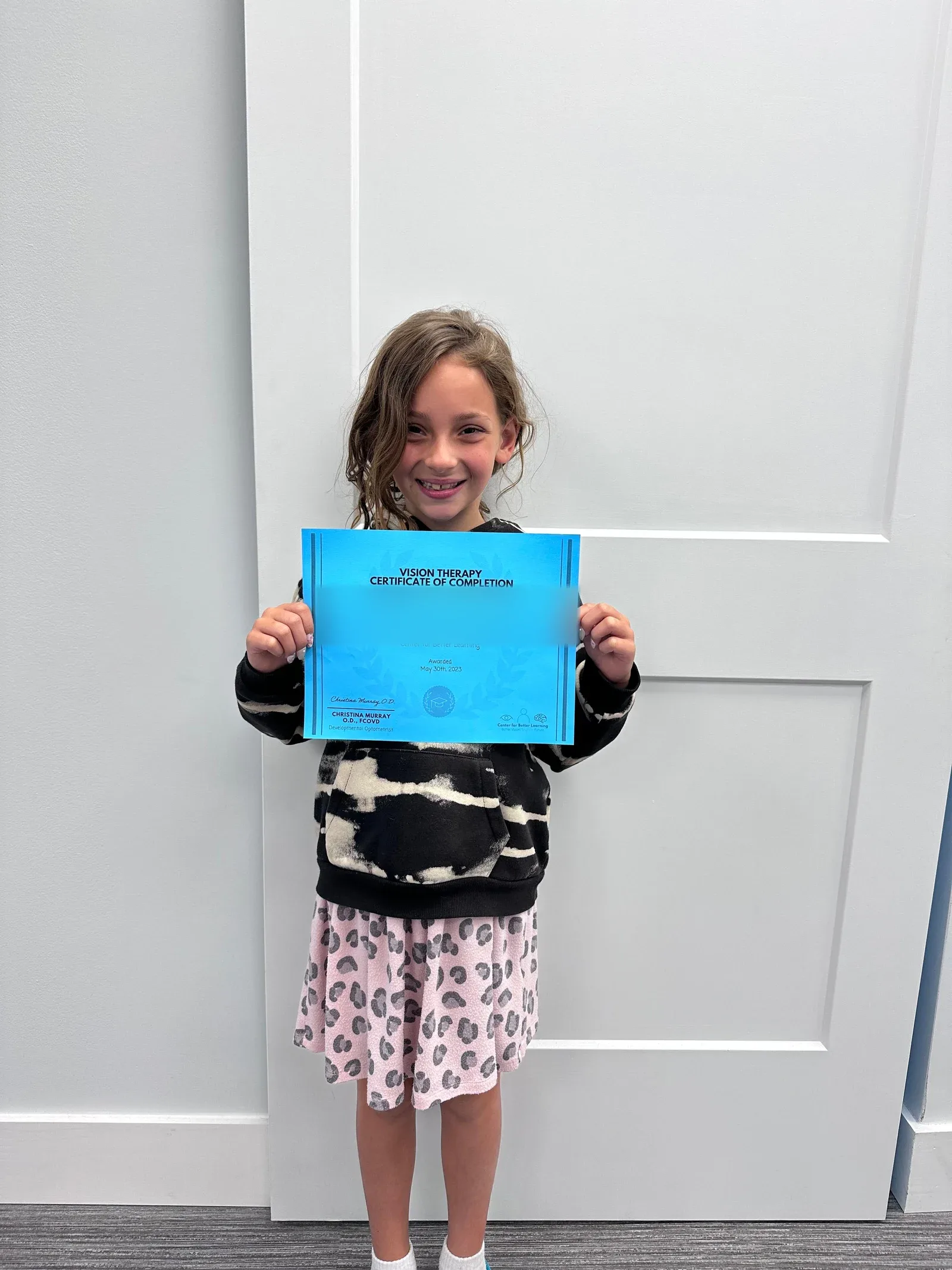 A vision therapy graduate holding their certificate