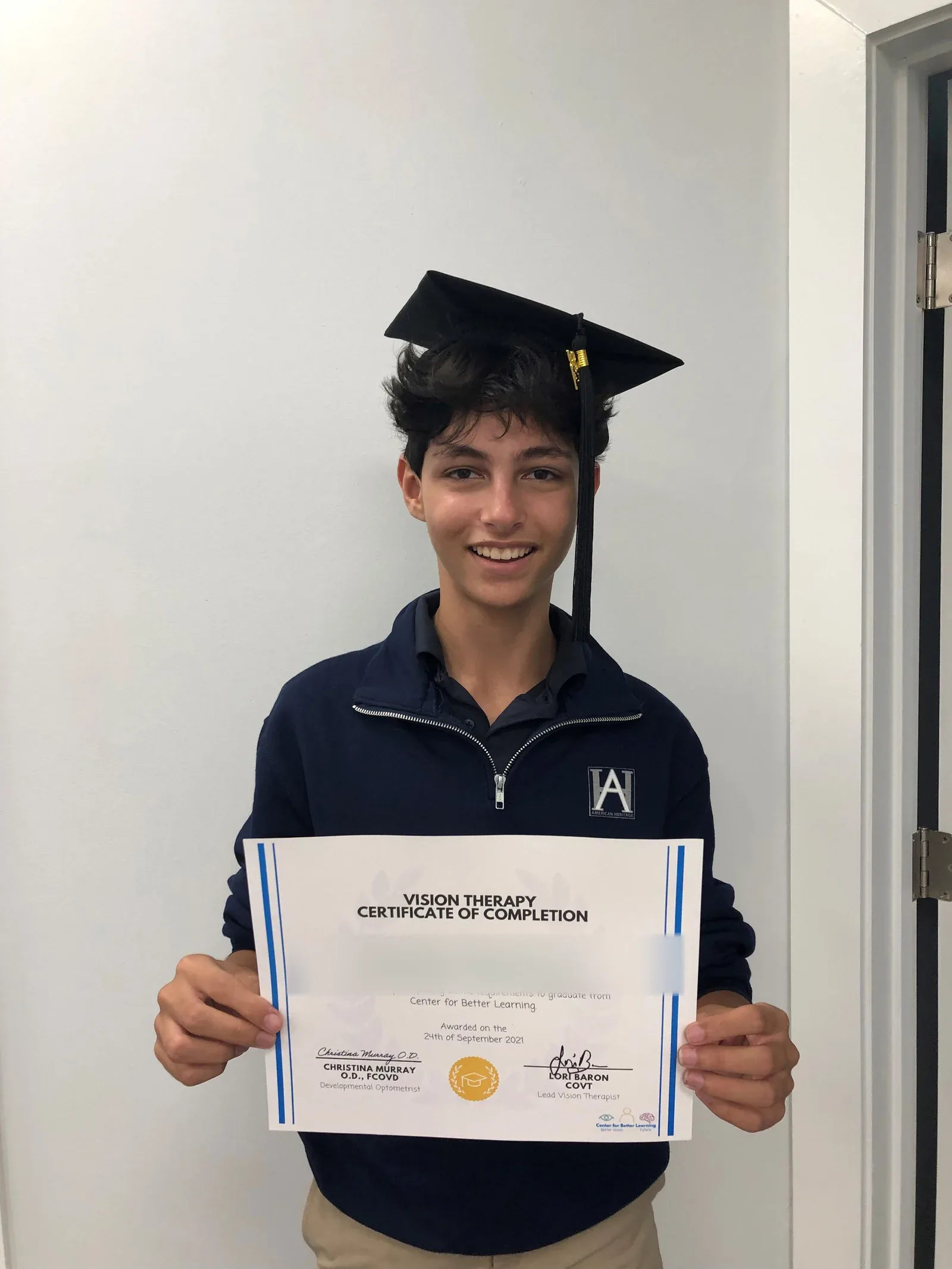 A vision therapy graduate holding their certificate