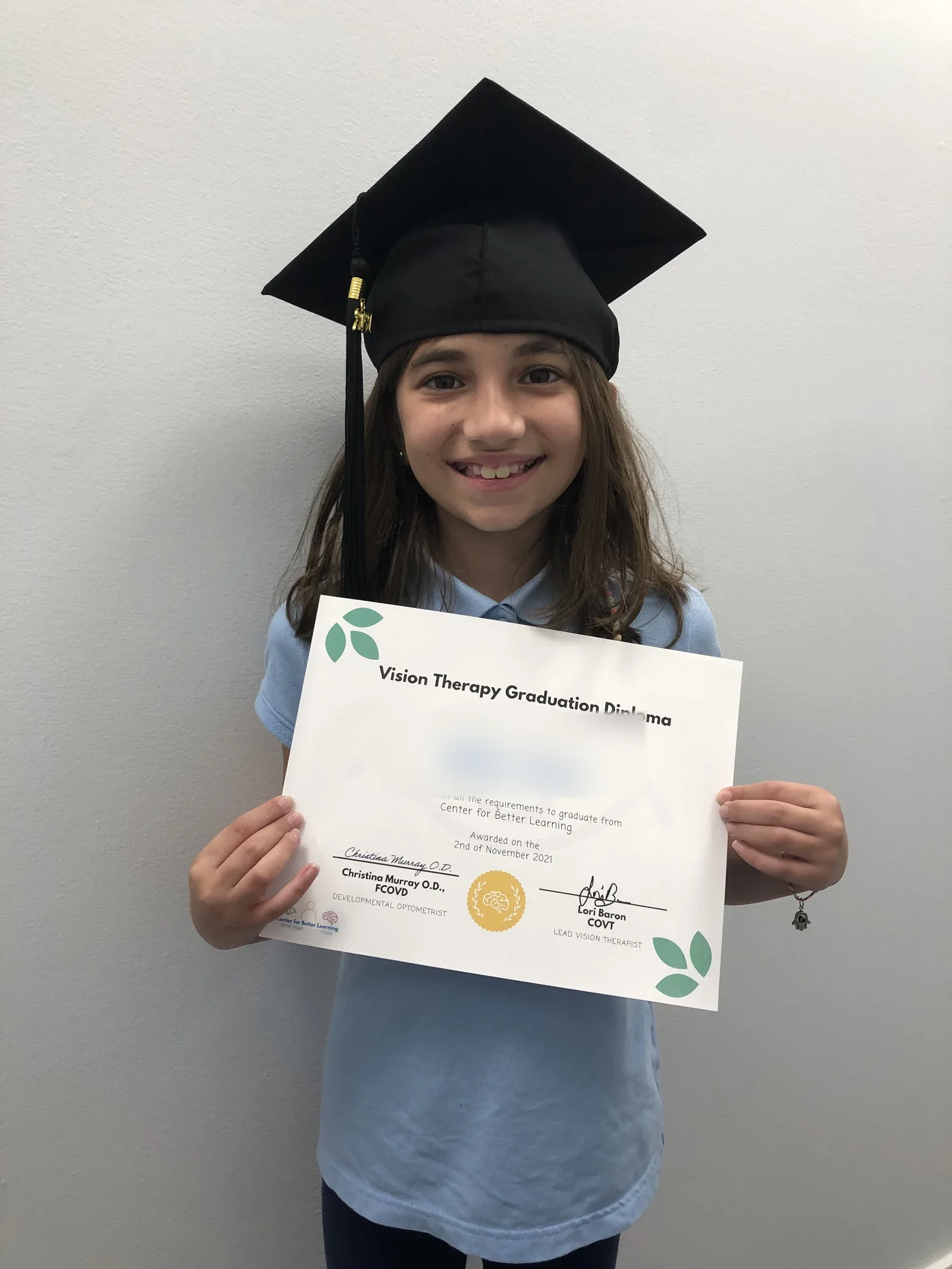 A vision therapy graduate holding their certificate
