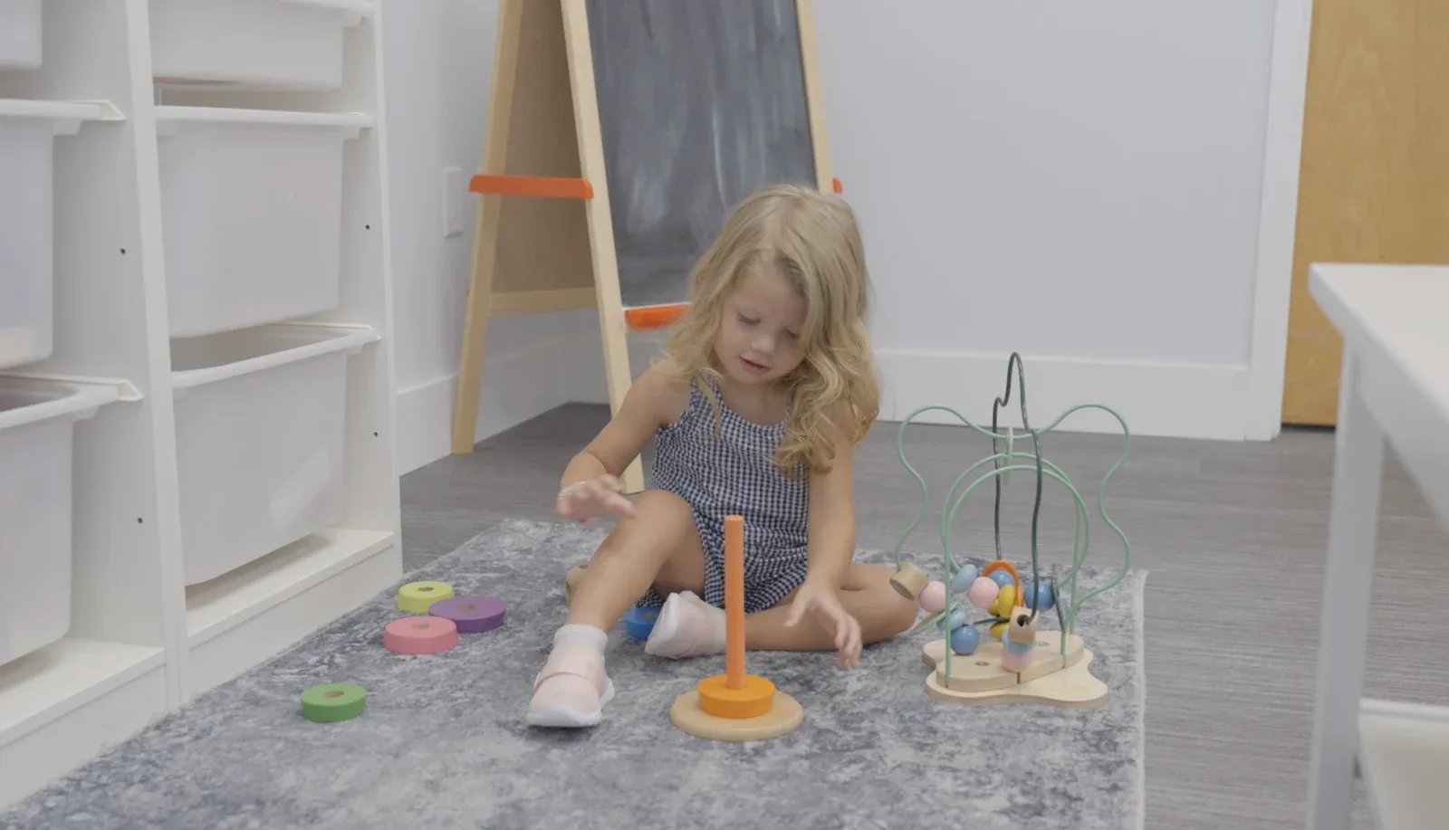 A child playing with toys on the rug in the play corner of the Coconut Creek office