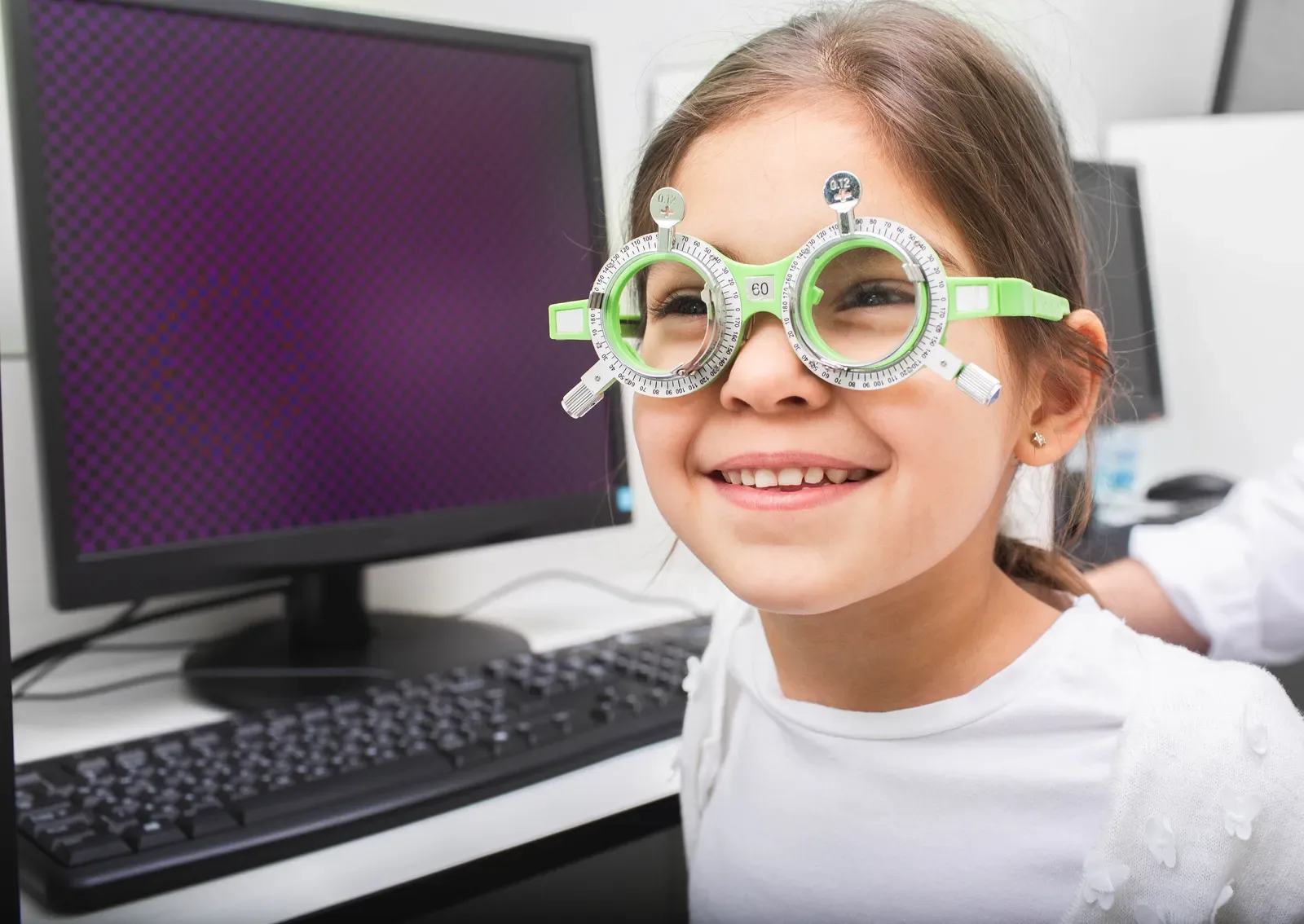 A smiling girl wearing a trial frame during an eye examination