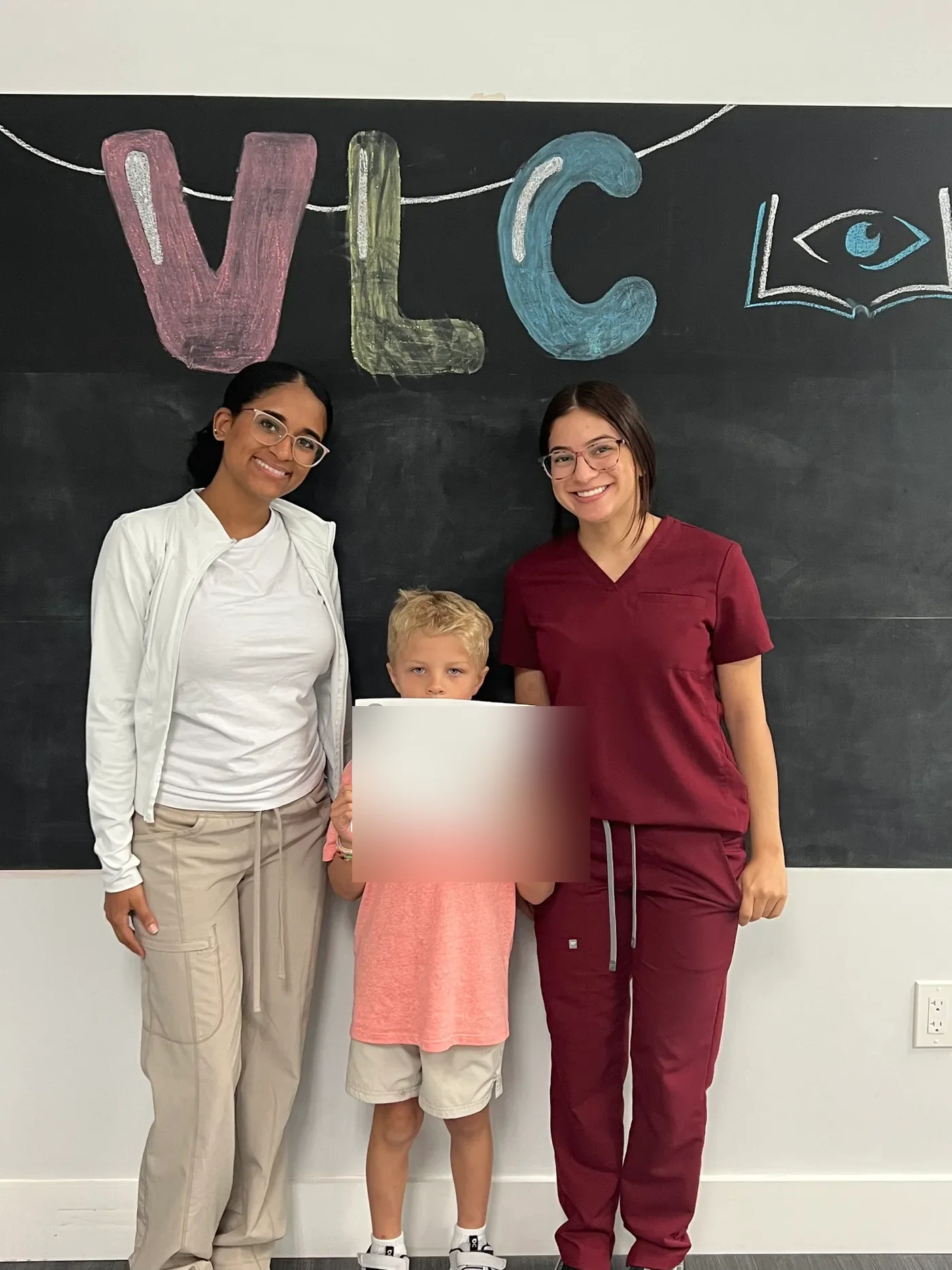 A young patient celebrating at their vision therapy graduation with a certificate
