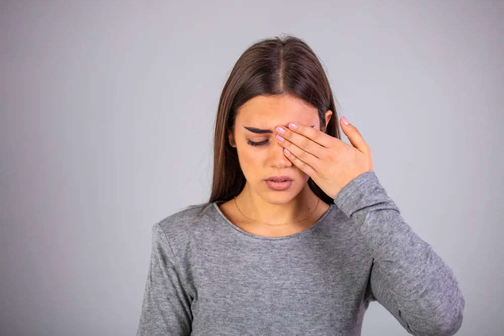A woman rubbing her eyes and looking away from her laptop after a long stretch of screen work