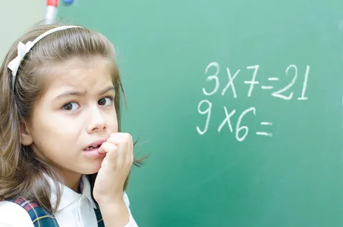 A child at the classroom whiteboard working through a math problem in front of the class