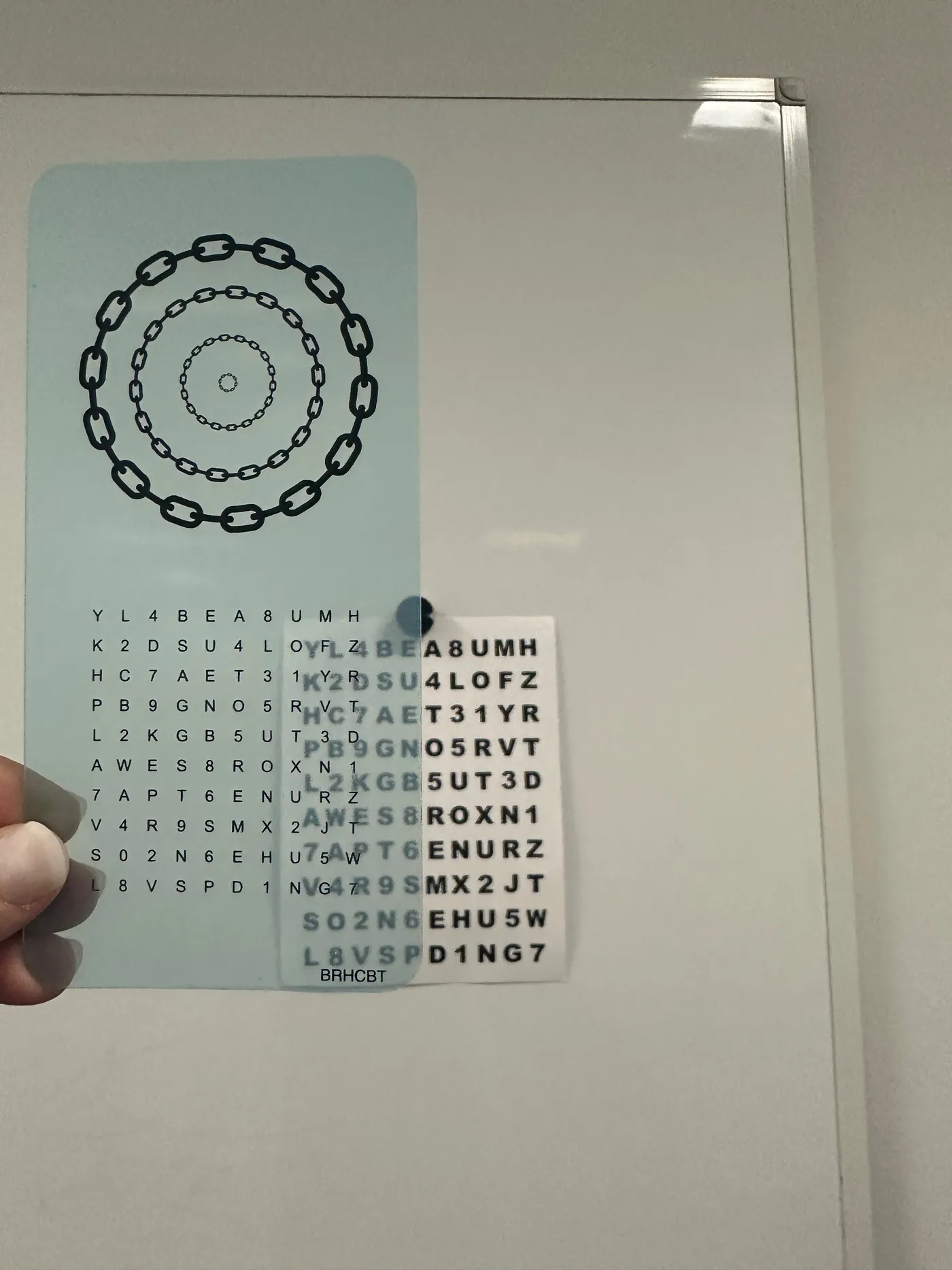 Two overlapping transparent training sheets held against a whiteboard during a vision therapy activity, each printed with a grid of letters and numbers.