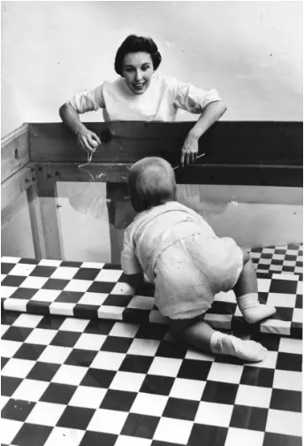 A baby on the shallow side of a visual cliff apparatus, a clear panel over a checkerboard floor